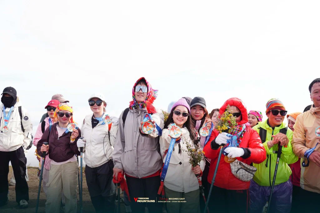 Các trekker cầm huy chương và bó hoa dại trên đỉnh Tà Chì Nhù