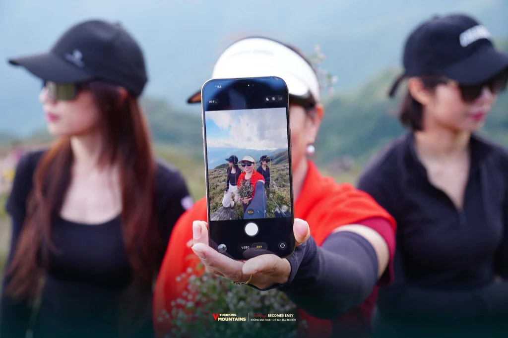 Ba cô gái chụp ảnh selfie bằng điện thoại trên sống núi Tà Chì Nhù mùa hoa Chi Pâu