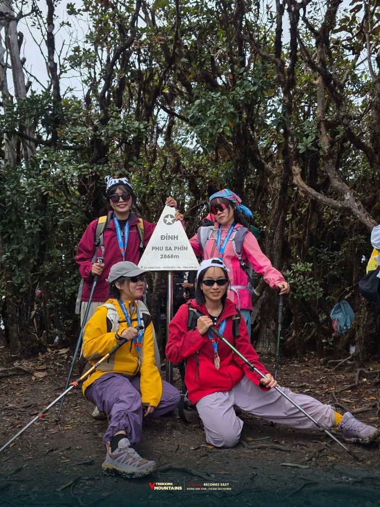 Bốn nữ trekker đeo huy chương bên cột mốc đỉnh Phu Sa Phìn 2868m