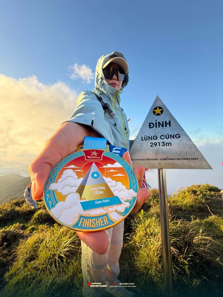 Huy chương Finisher VMountains Lùng Cúng 2913m bên cột mốc đỉnh Lùng Cúng