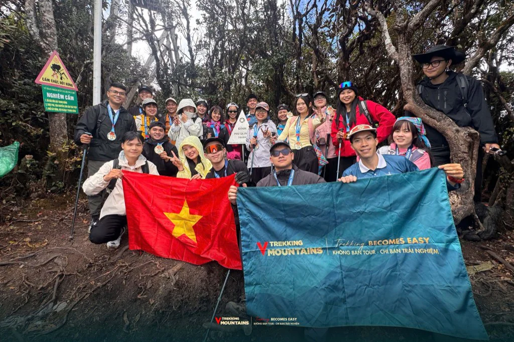 Đoàn VMountains cầm cờ Việt Nam và cờ VMountains bên cột mốc đỉnh Phu Sa Phìn
