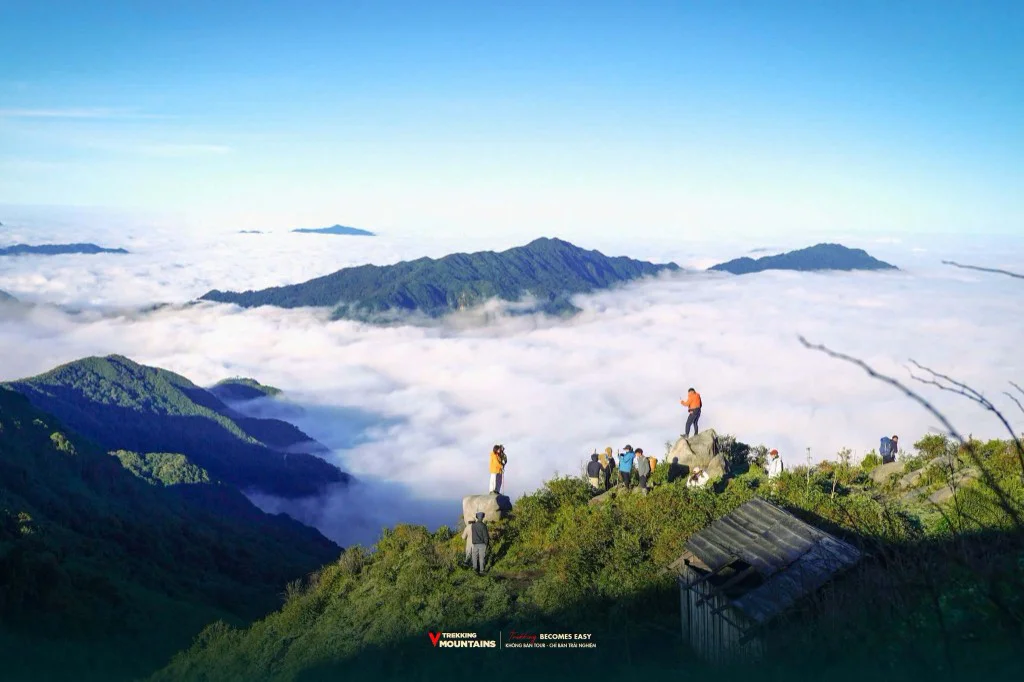 Đoàn trekking đứng trên mỏm đá ngắm biển mây trắng phủ kín thung lũng ở Lùng Cúng